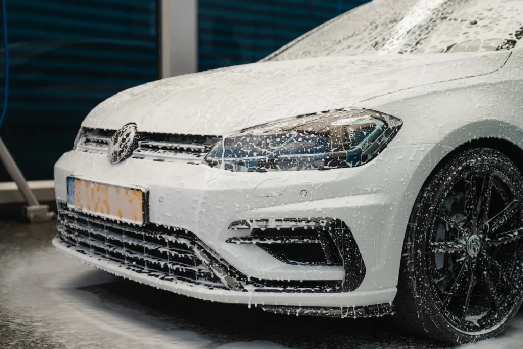 Witte Volkswagen Golf 7.5R onder het wasschuim tijdens een premium wasbeurt